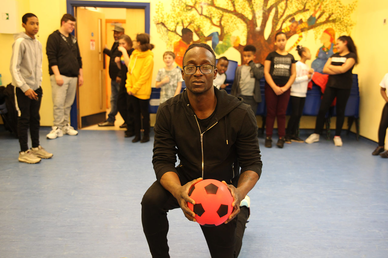 Emmanuel tenant une balle de football. 